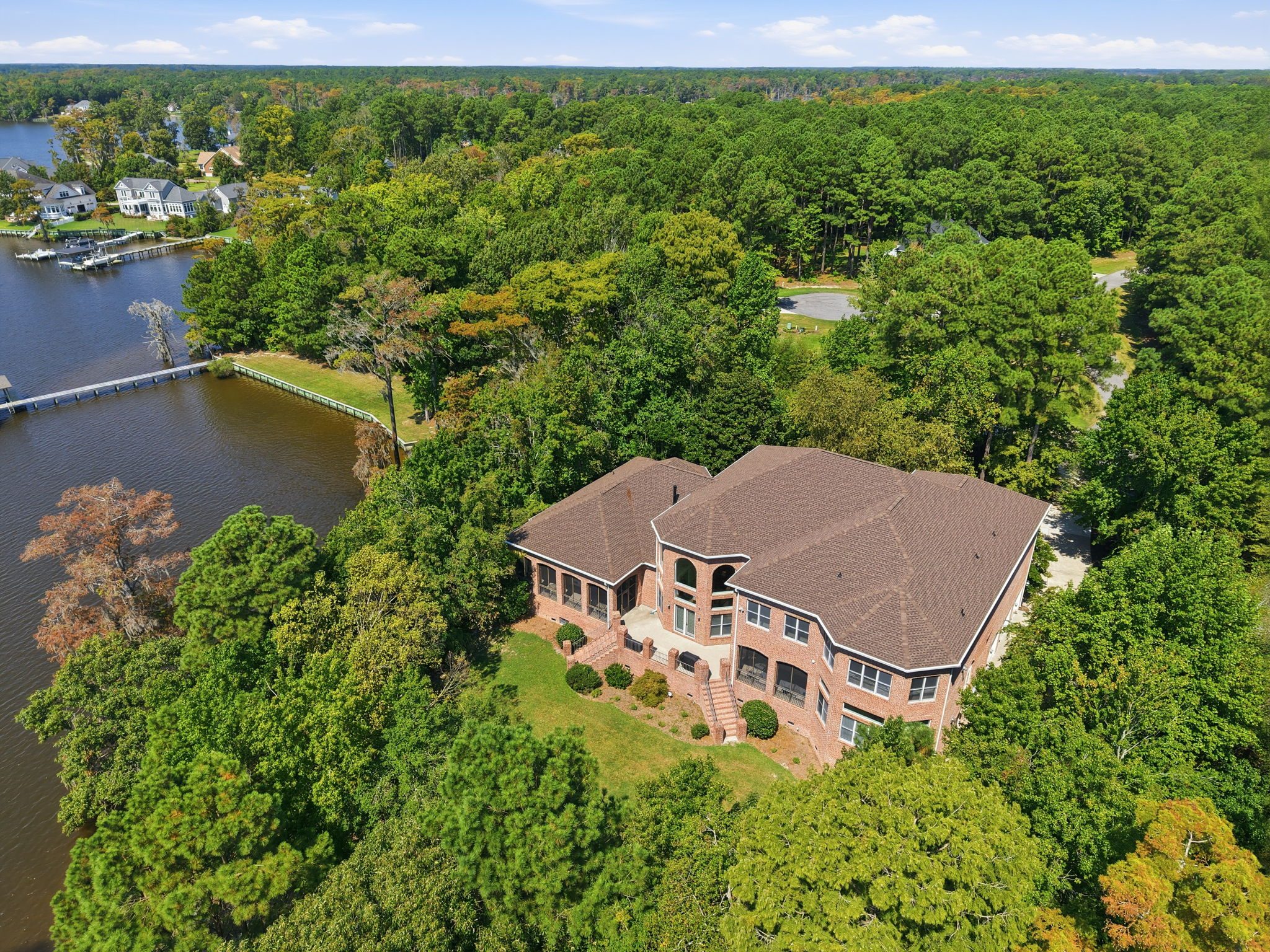 Aerial view of the brick estate among the trees beside the water